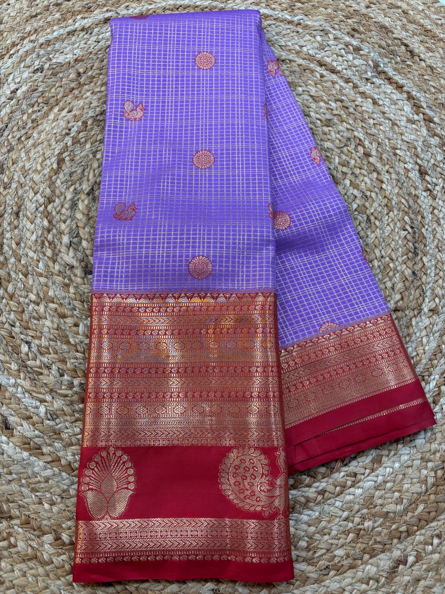 lavendar and red saree with intricate patterns on a textured surface