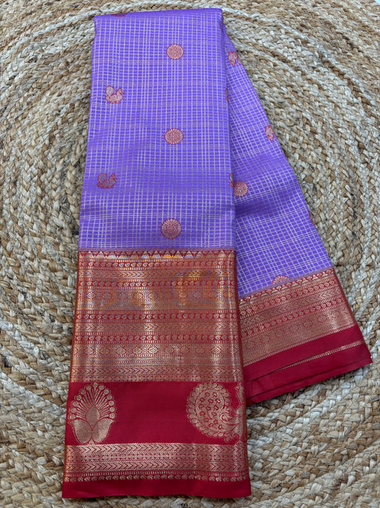lavendar and red saree with intricate patterns on a textured surface